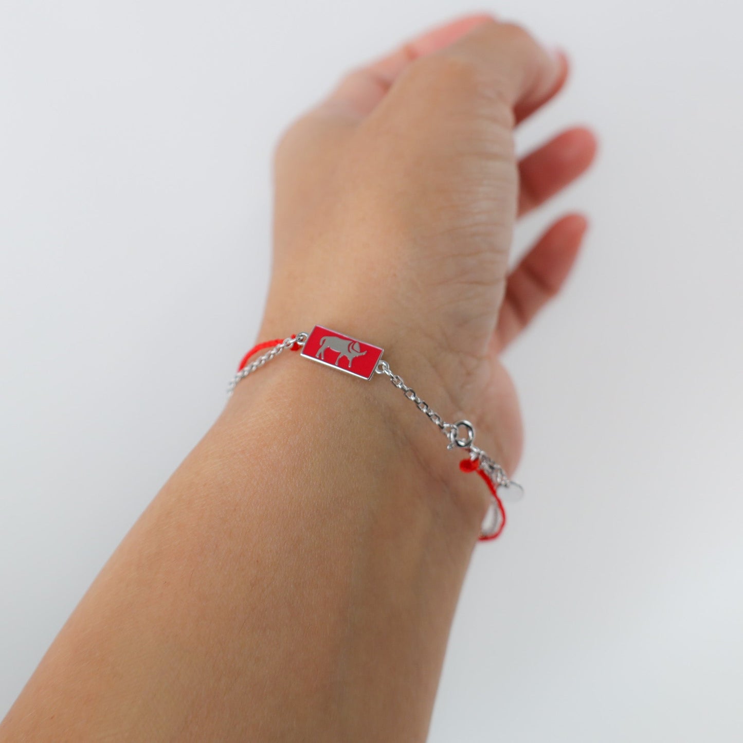 Ox zodiac red string bracelet with white gold chain, flat lay - Crowned