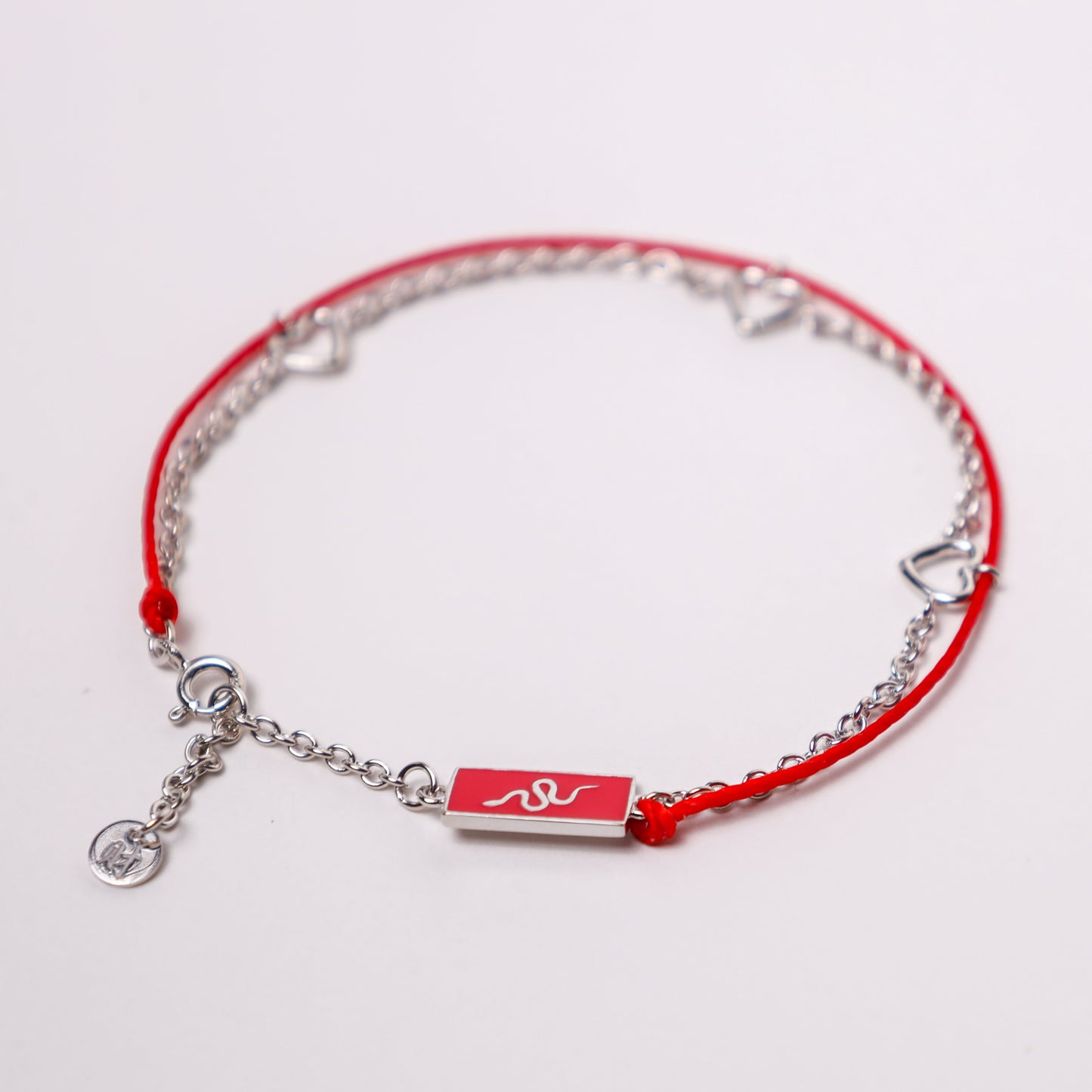 Snake zodiac red string bracelet with white gold chain, flat lay - Crowned